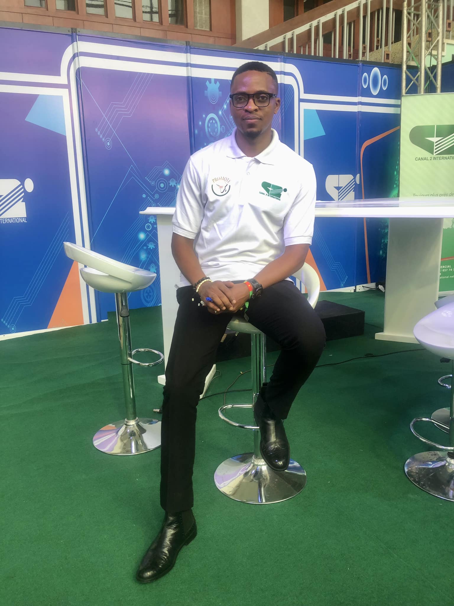 Stephane Lando smiling in a red plaid shirt and tortoise shell glasses